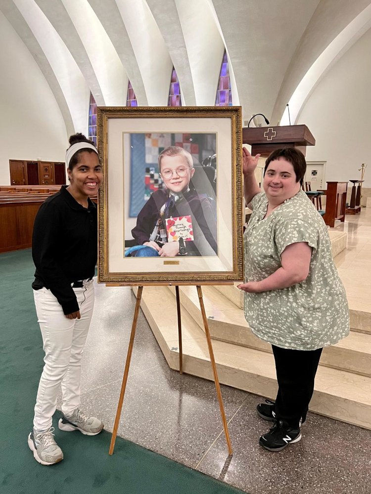 Two women with photo of Mattie at the mass